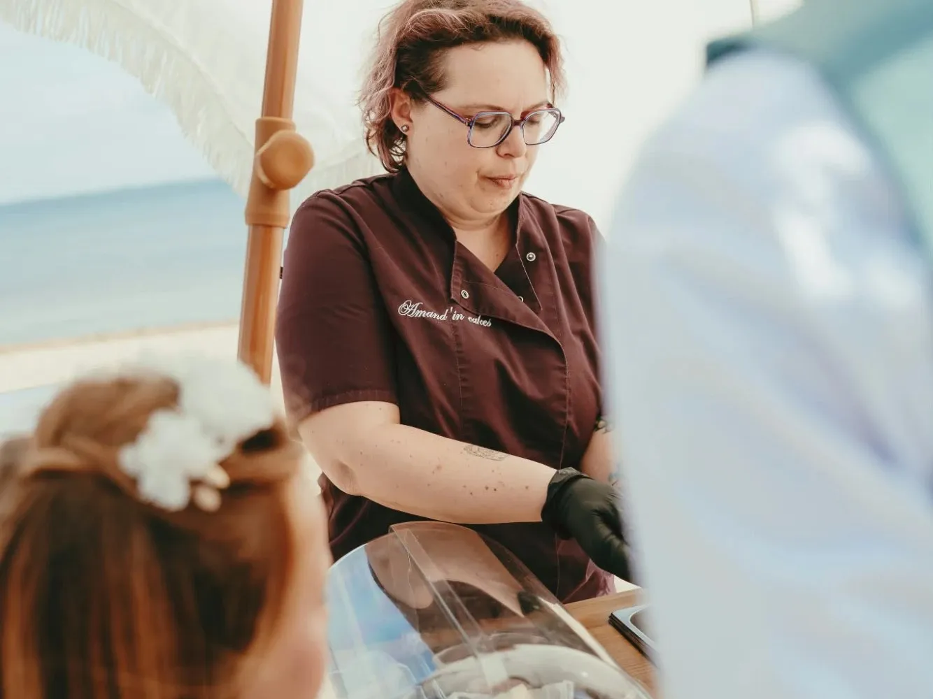 Amandine sert ses pâtisseries sous un parasol, face au bassin