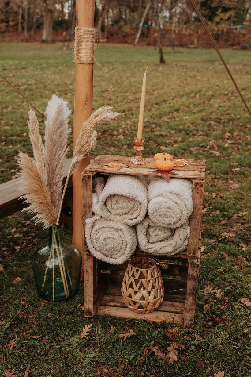 Caisse en bois garnie de plaids roulés, pampas et petite citrouille