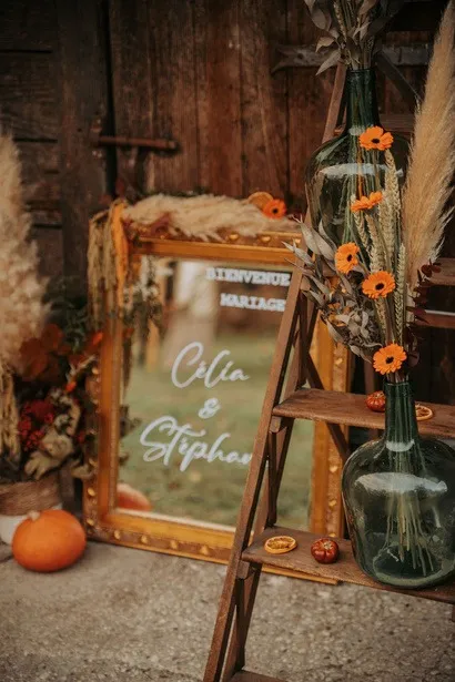 Miroir doré de bienvenue aux prénoms des mariés, fleurs orange et pampas