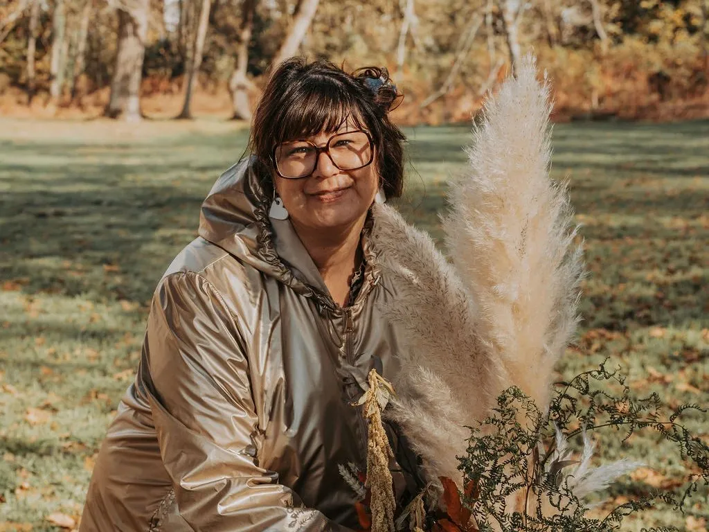 Céline compose un bouquet de pampas et de feuillages d’automne, dehors