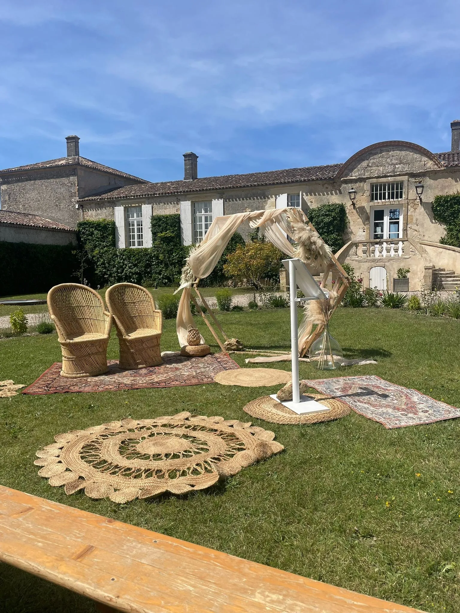 Arche bohème, fauteuils en rotin et tapis ronds dans le jardin d'un château