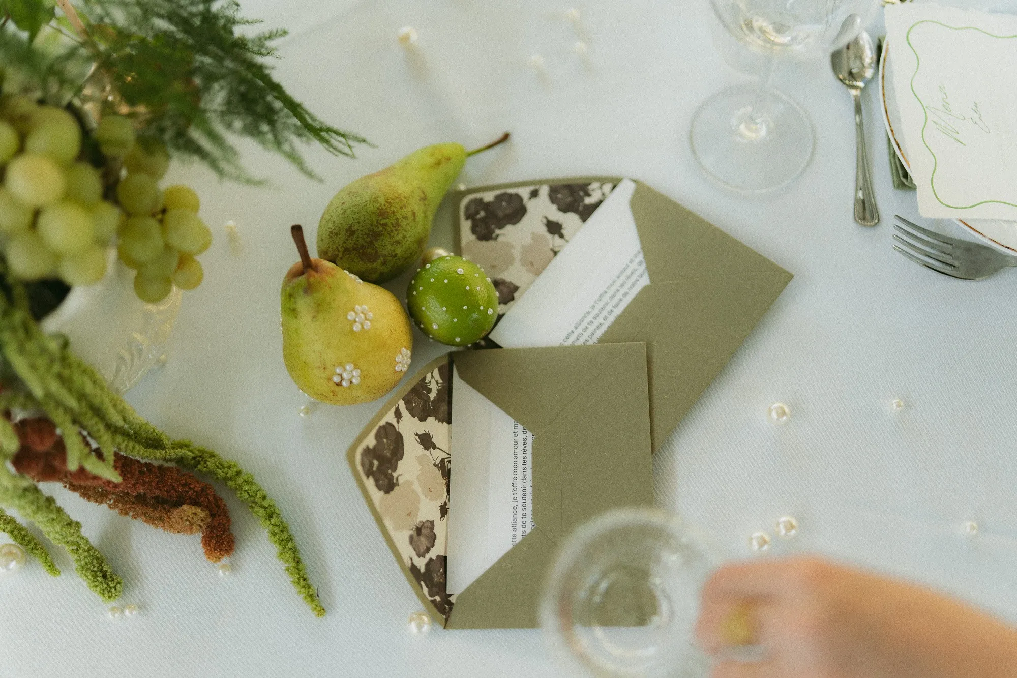 Enveloppe kaki, poires et raisins sur une table dressée