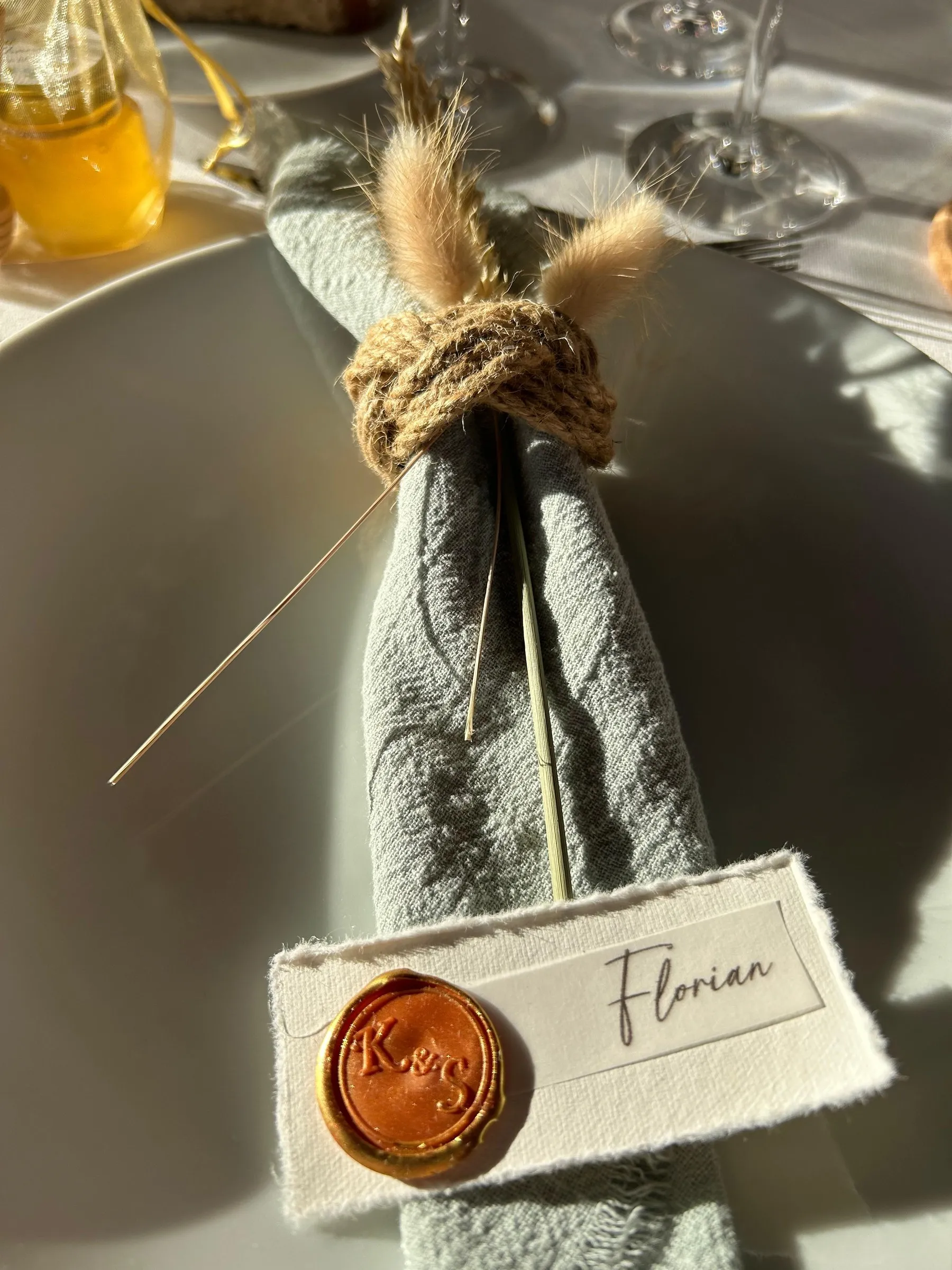 Marque-place au prénom de Florian, scellé à la cire dorée, glissé dans une serviette nouée