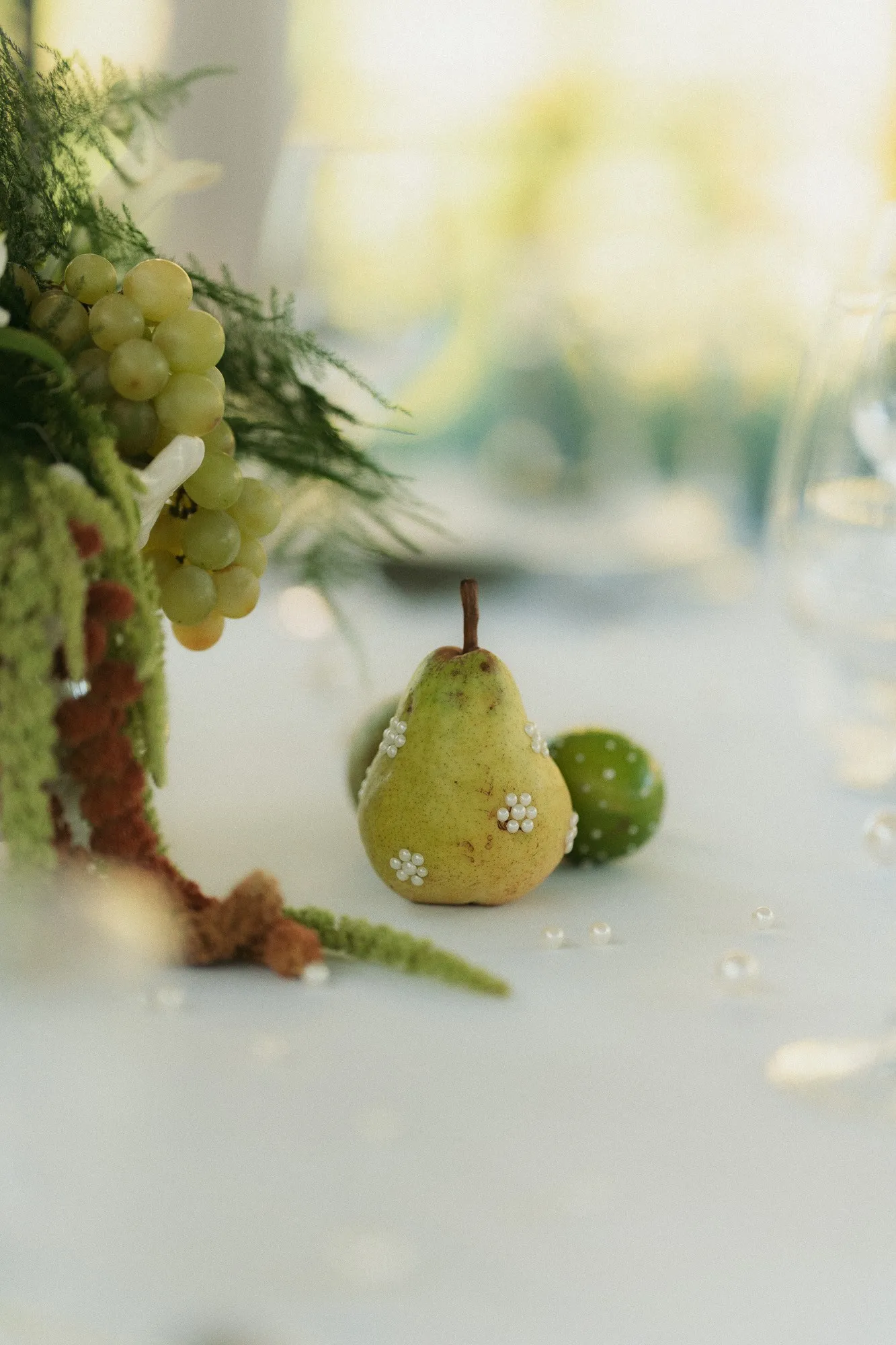 Poire ornée de petites fleurs blanches au pied d'un centre de table en raisins