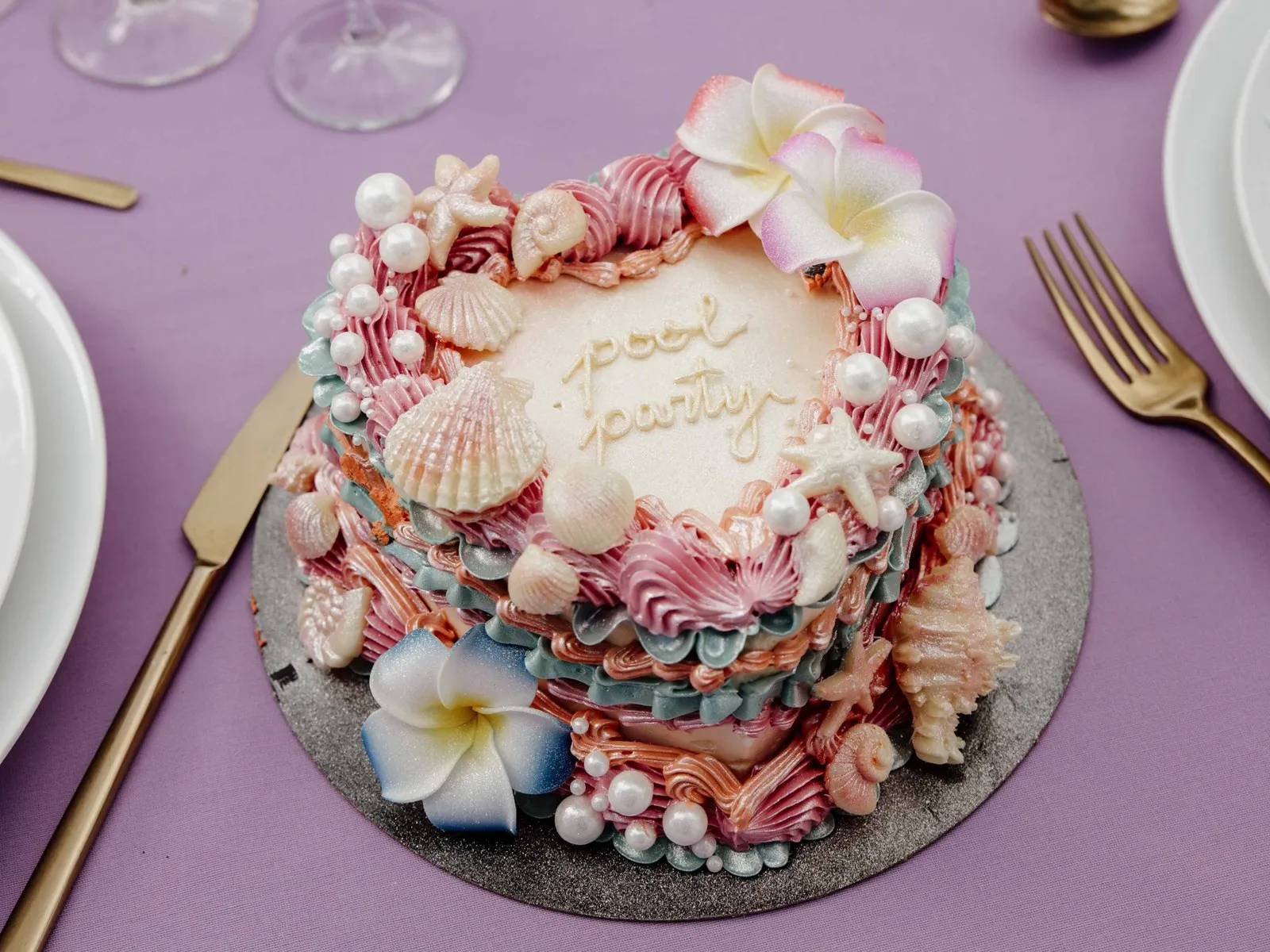 Gâteau pastel décoré de coquillages et de perles, sur une table dressée