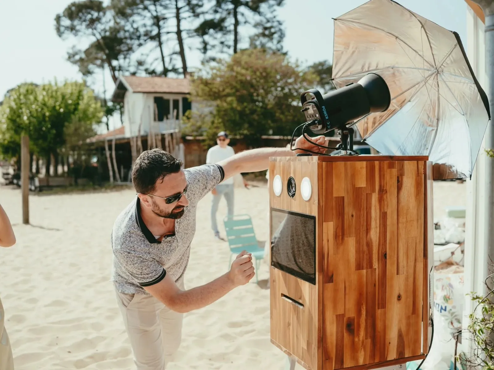 Installation de la borne photo en bois sur le sable, face aux cabanes