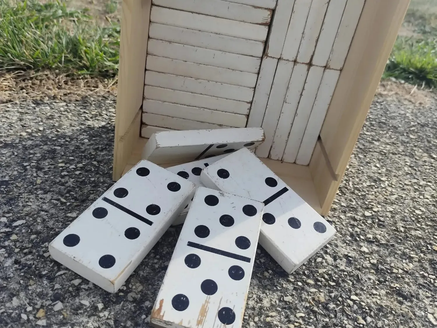 Dominos géants en bois peint, posés devant leur caisse en bois clair