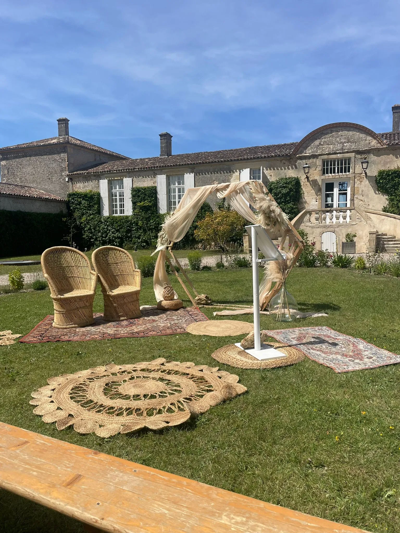 Deux fauteuils en osier posés sur un tapis ancien, devant un château