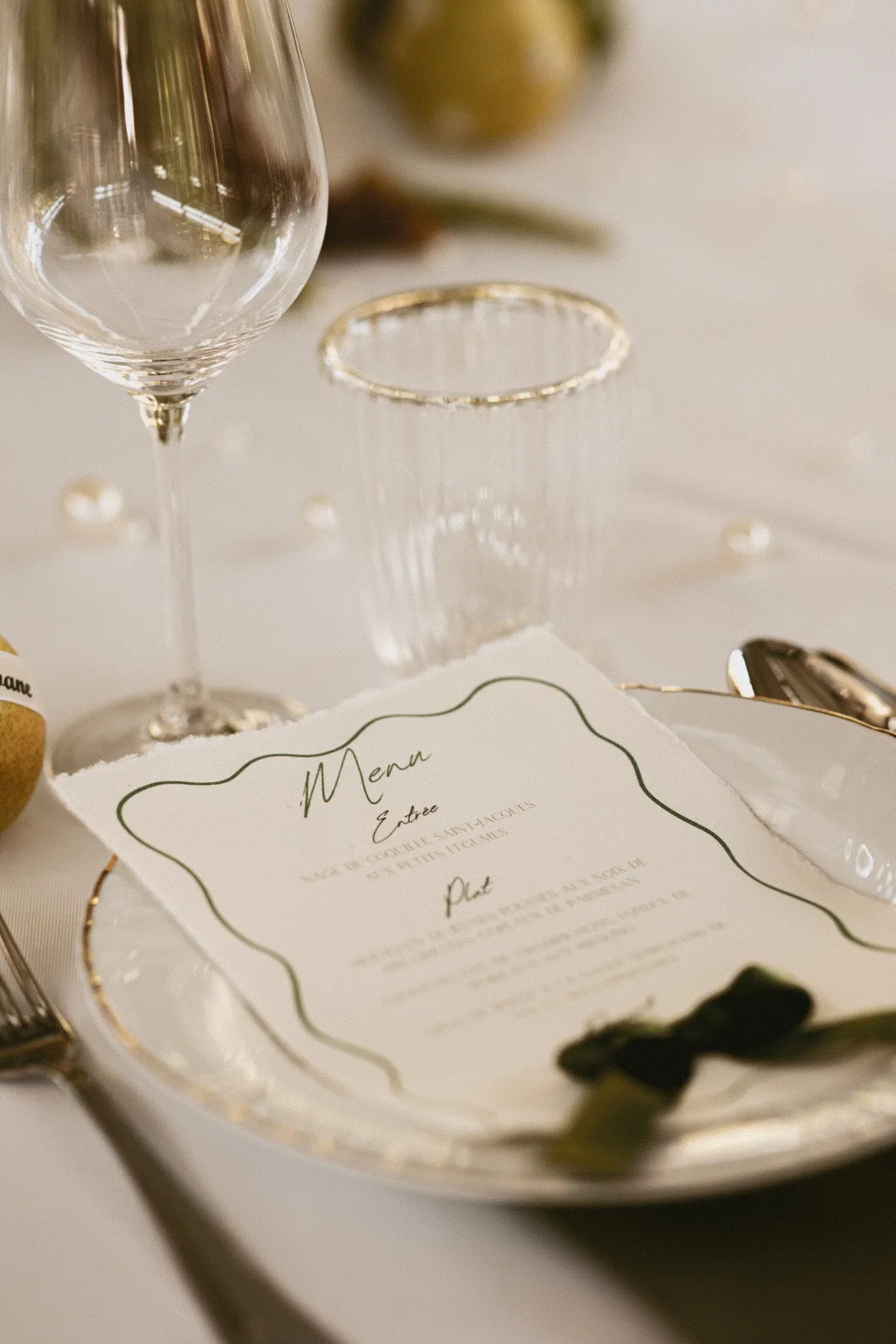Menu calligraphié posé sur une assiette à bord doré