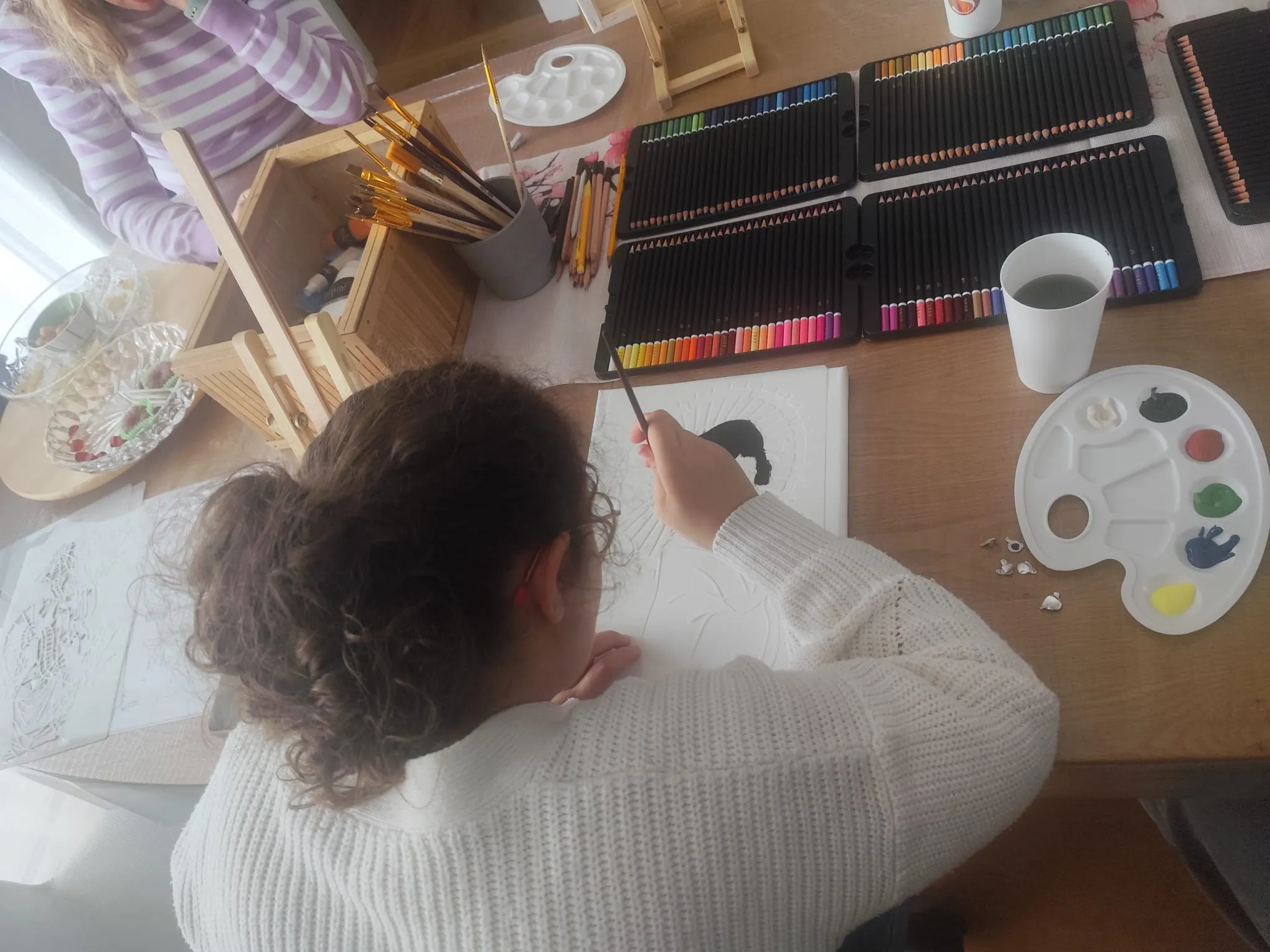 Atelier peinture : palettes, pinceaux et crayons de couleur sur la table