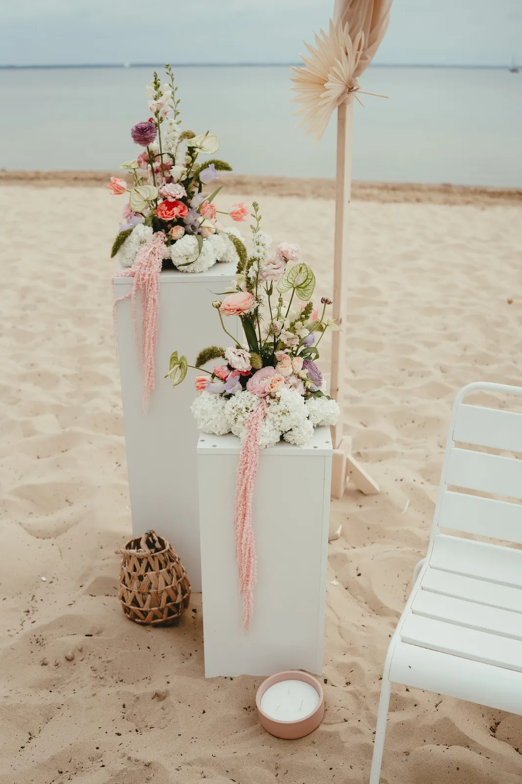 Colonnes blanches fleuries de roses et d'œillets plantées dans le sable