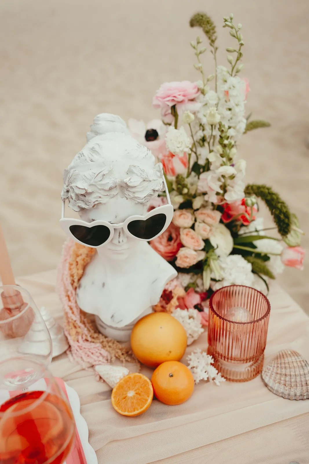 Buste à l'antique coiffé de lunettes de soleil, entouré de fleurs et d'agrumes