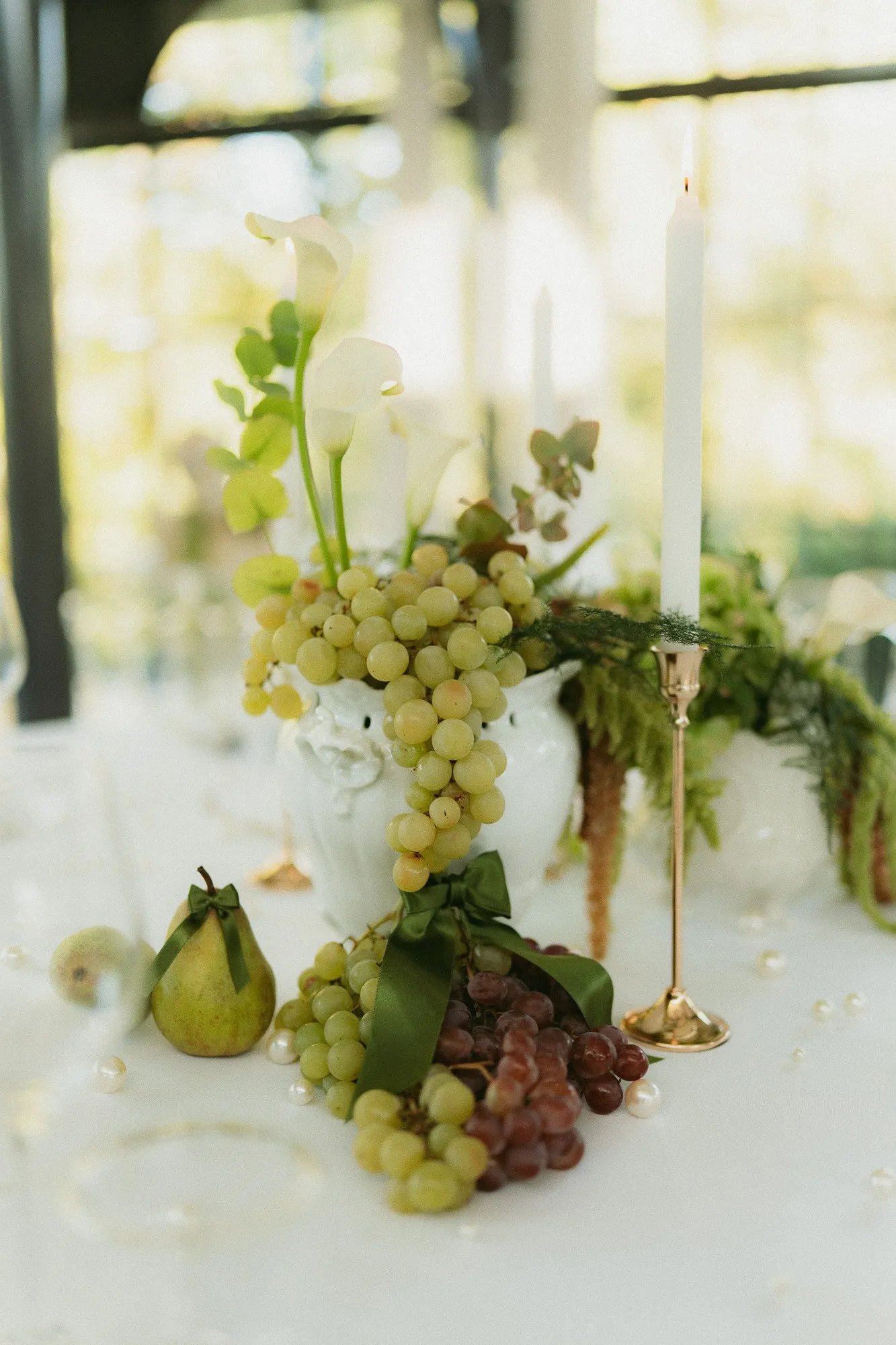 Centre de table en raisins, feuillages et poires sur une nappe blanche