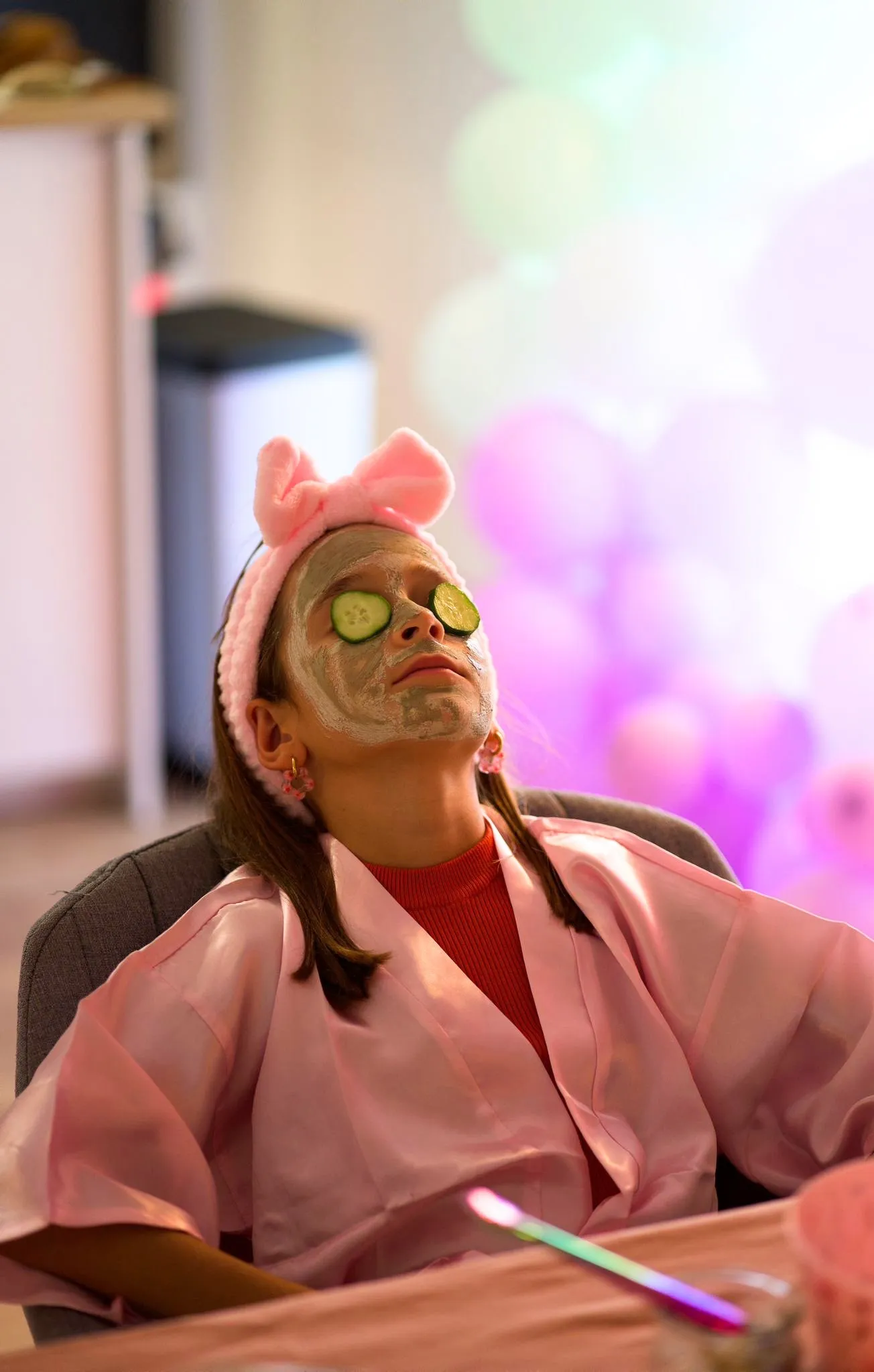 Une invitée en peignoir rose, masque et bandeau à nœud