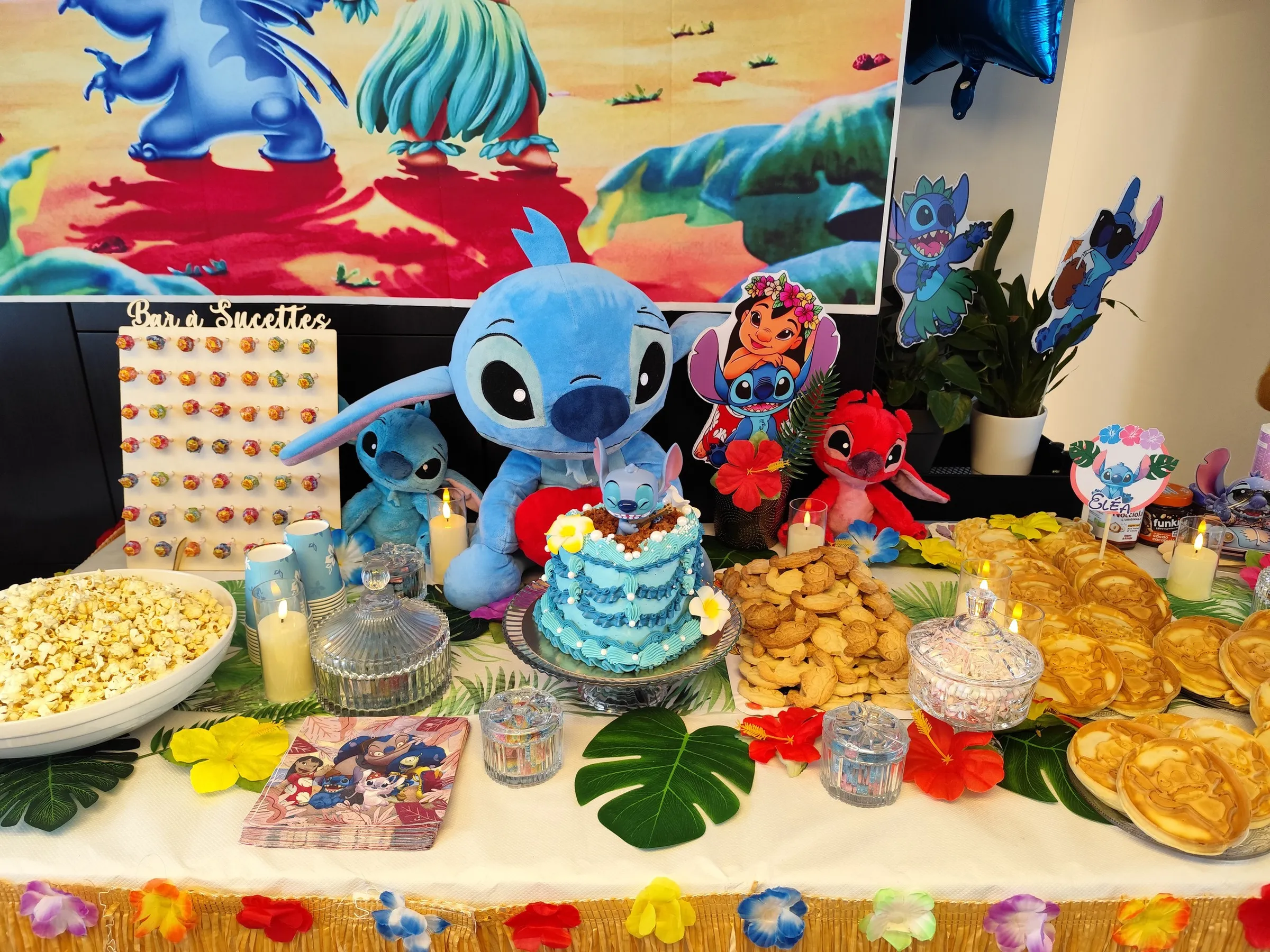 Table d'anniversaire Stitch : gâteau, peluches et feuilles de palmier