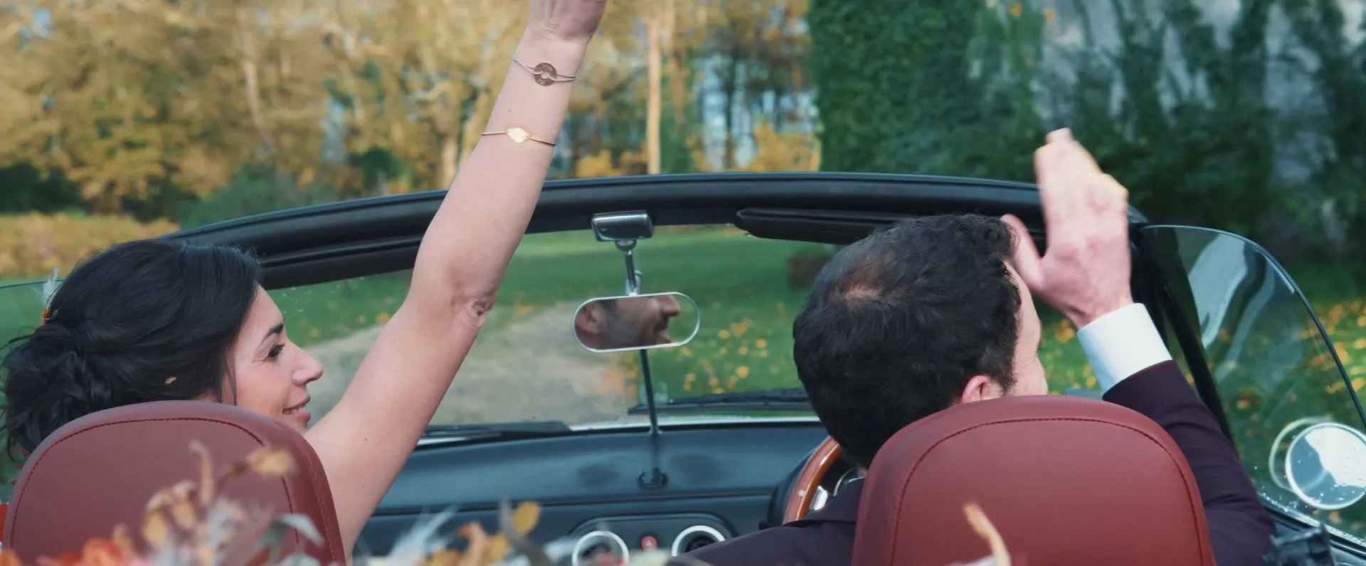 Les mariés dans un cabriolet, sous les arbres dorés du domaine